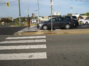 Car in crosswalk, man crossing