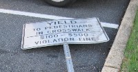 Downed sign about yielding to pedestrians