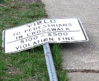 Downed sign about yielding to pedestrians